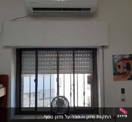 מזגן מותקן מעל חלון עם מאוורר קטן